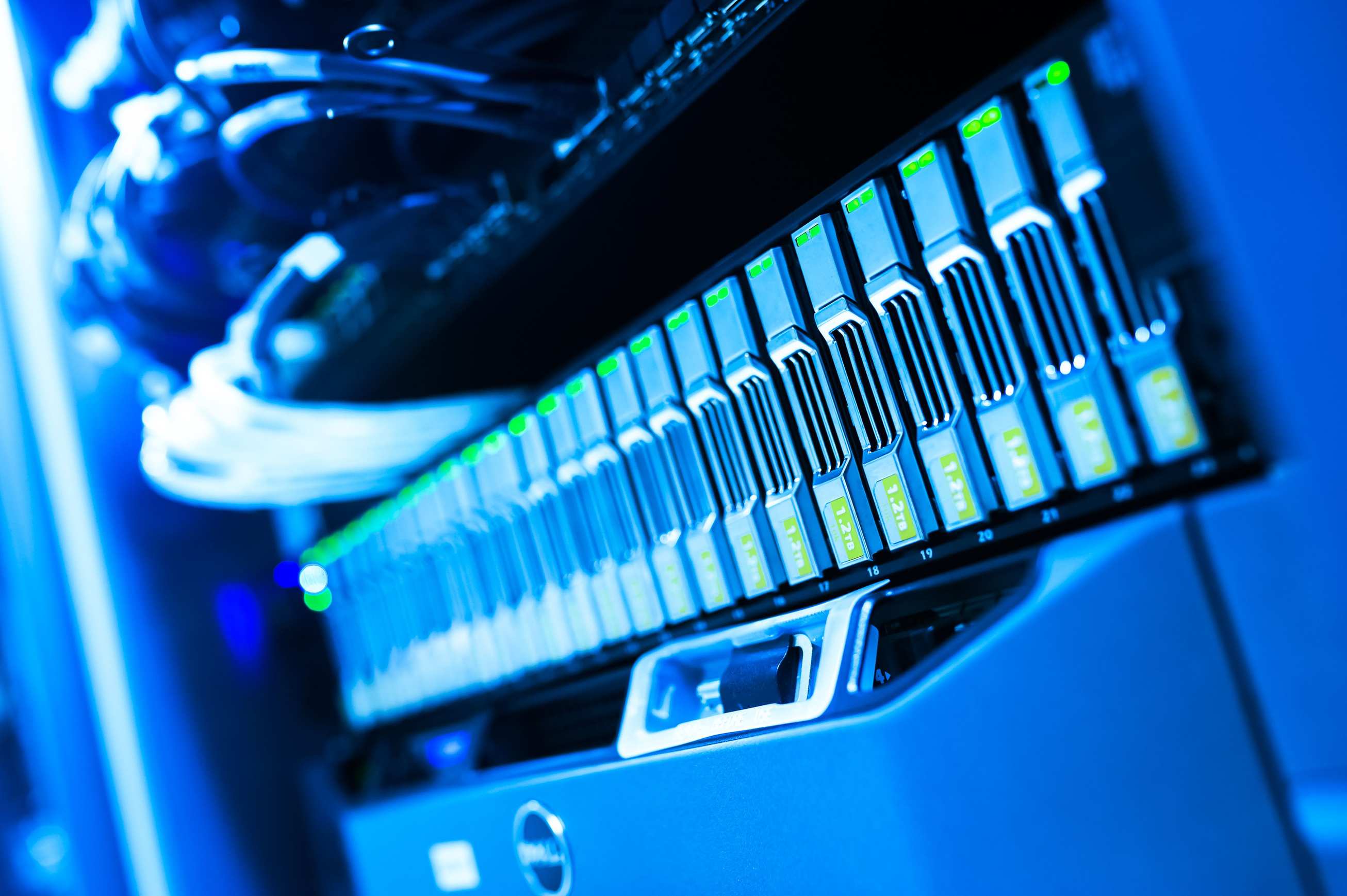 Rows of server racks in a data centre aisle with blue-lit computer hardware